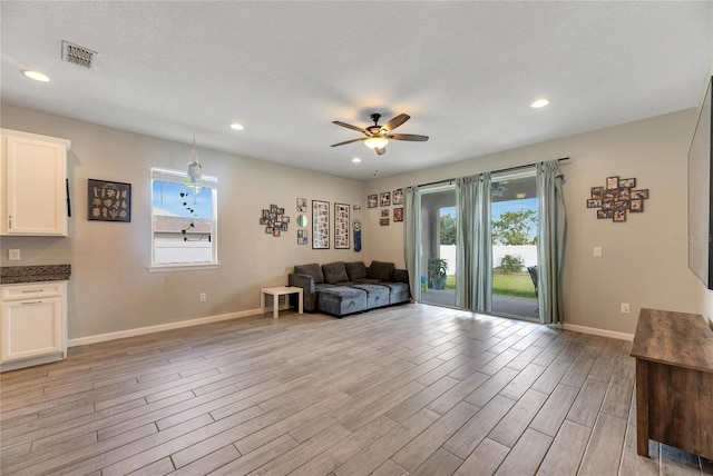 living room featuring ceiling fan, a textured ceiling, and light hardwood / wood-style flooring