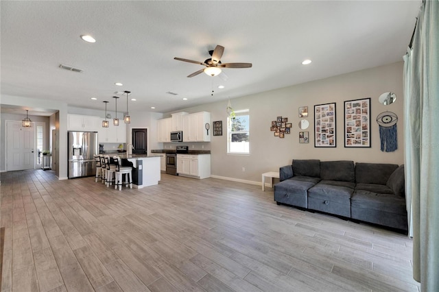 living room with sink, ceiling fan, and light hardwood / wood-style floors