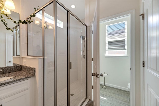 bathroom featuring an enclosed shower, hardwood / wood-style floors, toilet, and vanity