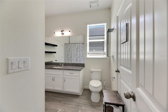 bathroom with wood-type flooring, toilet, and vanity