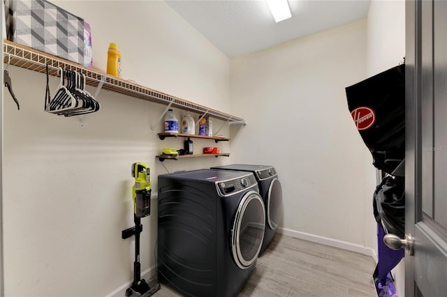 laundry area with washer and clothes dryer and light hardwood / wood-style flooring