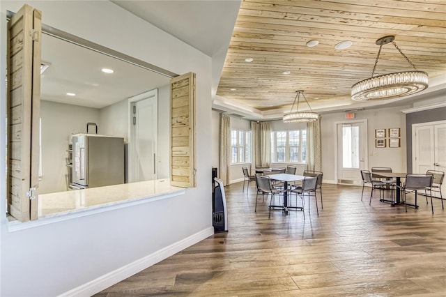 dining space featuring a tray ceiling, dark wood-type flooring, a notable chandelier, and wood ceiling