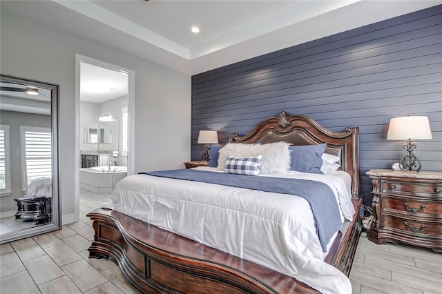 bedroom with wood walls, light hardwood / wood-style floors, and ensuite bath