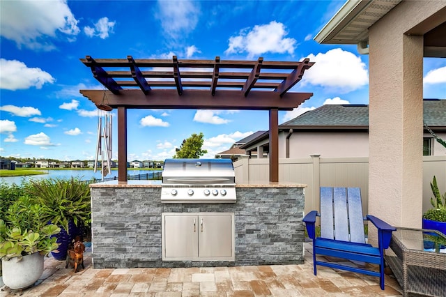 view of patio featuring a pergola, grilling area, a water view, and an outdoor kitchen