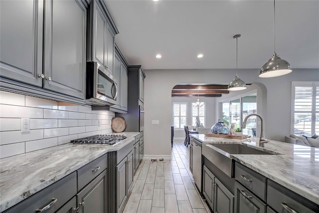 kitchen with appliances with stainless steel finishes, gray cabinets, plenty of natural light, and sink