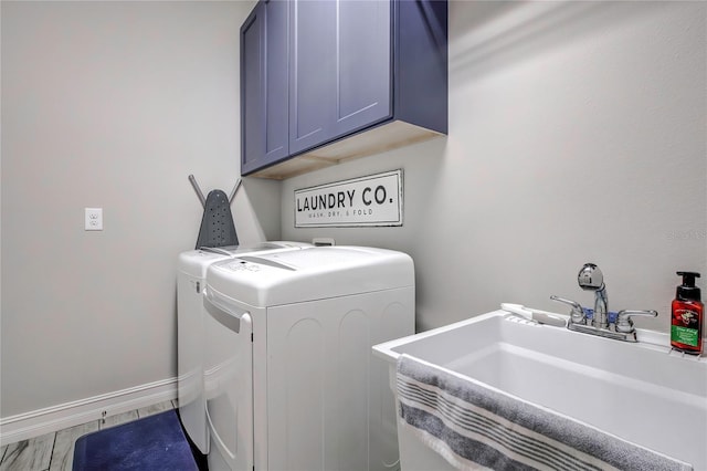 clothes washing area with washing machine and clothes dryer, cabinets, and sink