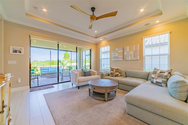 living room with a tray ceiling, crown molding, and ceiling fan