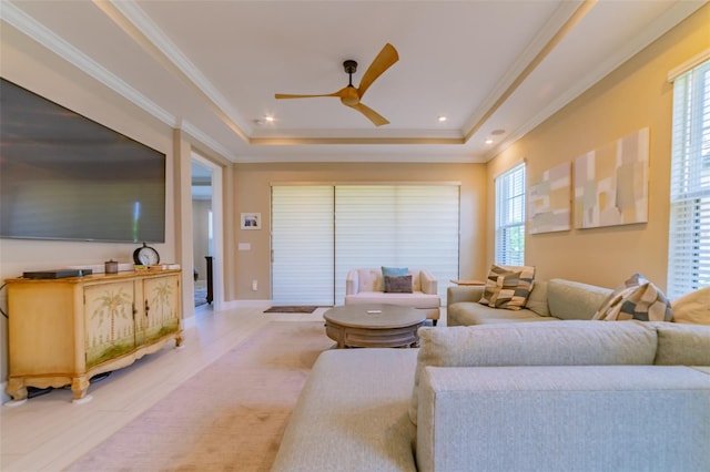 carpeted living room featuring crown molding, a tray ceiling, and ceiling fan