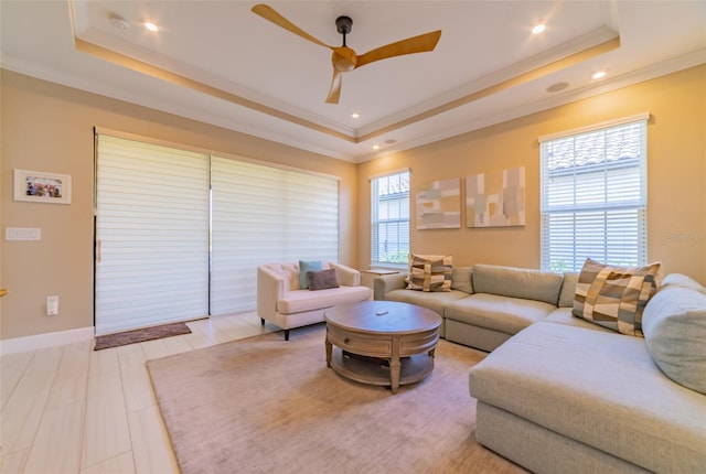 living room featuring a healthy amount of sunlight, ceiling fan, and a raised ceiling