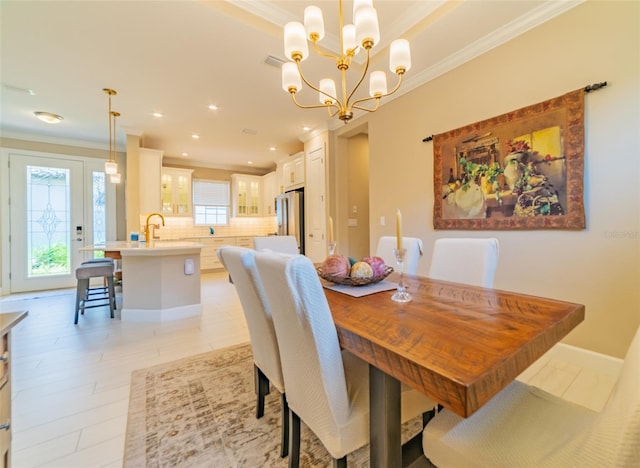 dining room featuring ornamental molding, a chandelier, sink, and light hardwood / wood-style floors