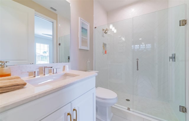 bathroom featuring toilet, a shower with door, and vanity