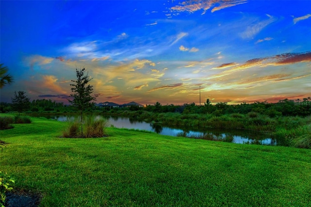 yard at dusk featuring a water view