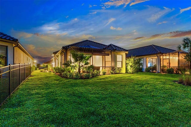 back house at dusk with a lawn