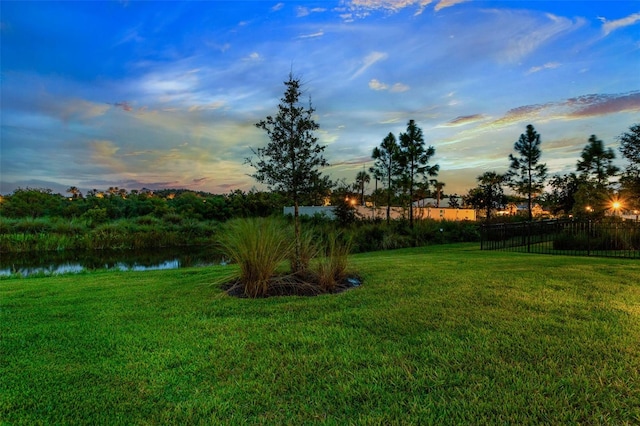 yard at dusk featuring a water view