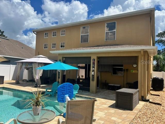 back of house with a fenced in pool and a patio