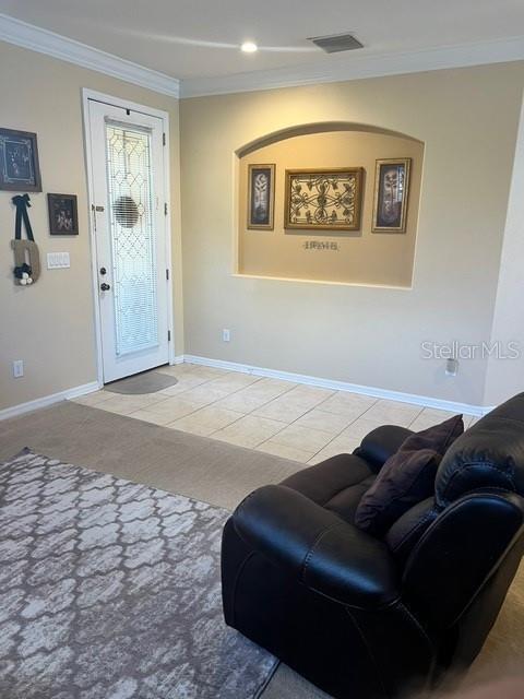 living room with light tile patterned floors and ornamental molding