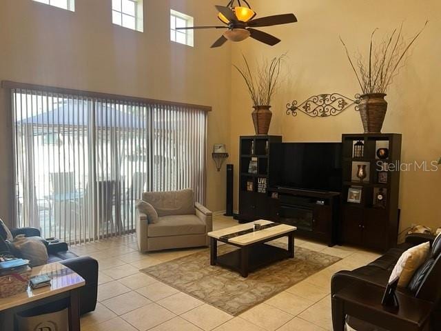 tiled living room with ceiling fan and a high ceiling