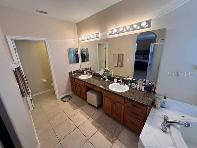 bathroom with tile patterned flooring, toilet, a washtub, and vanity