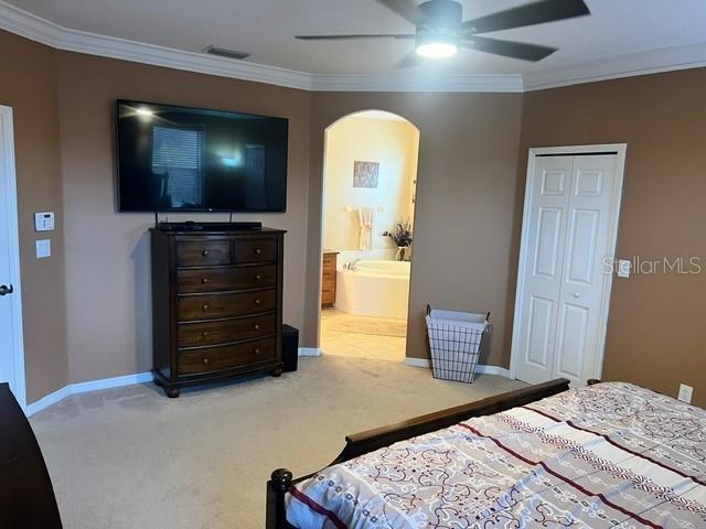 bedroom featuring crown molding, a closet, carpet floors, ceiling fan, and connected bathroom