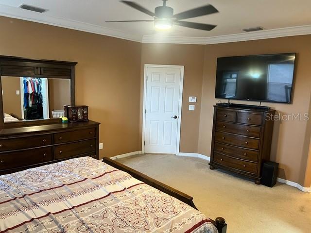 bedroom featuring ceiling fan, crown molding, and light carpet