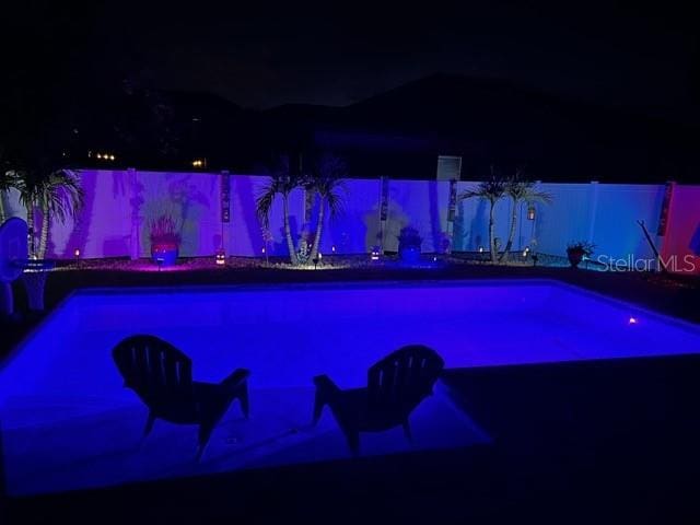 view of pool at twilight