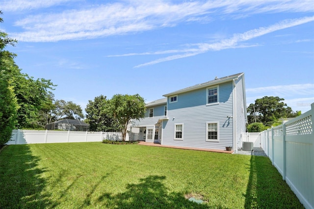 rear view of house with central AC unit and a yard