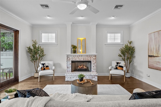 living room featuring crown molding, a brick fireplace, wood-type flooring, and ceiling fan