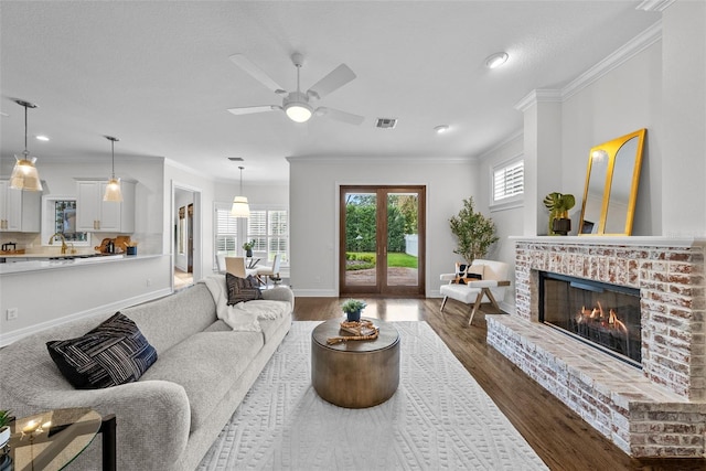 living room with crown molding, a healthy amount of sunlight, hardwood / wood-style floors, and a fireplace