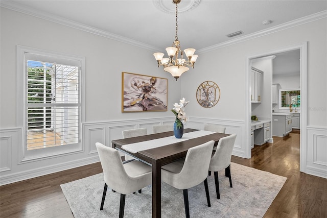 dining area with ornamental molding, dark hardwood / wood-style floors, and an inviting chandelier