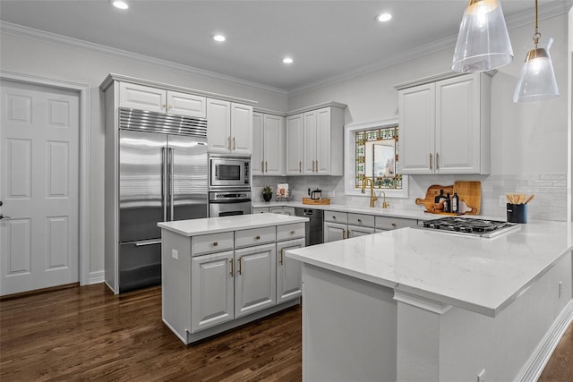 kitchen with crown molding, dark hardwood / wood-style floors, built in appliances, light stone counters, and tasteful backsplash