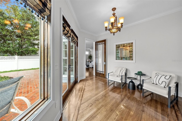 interior space with crown molding, wood-type flooring, a healthy amount of sunlight, and an inviting chandelier