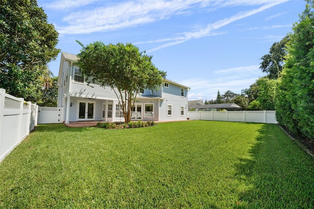 rear view of house featuring a patio, a yard, and french doors