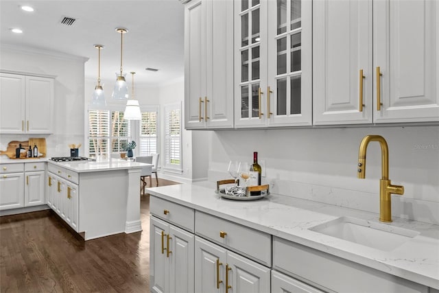 kitchen with white cabinetry, light stone countertops, sink, and pendant lighting