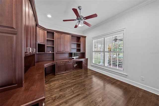 office space with crown molding, dark wood-type flooring, built in desk, and ceiling fan