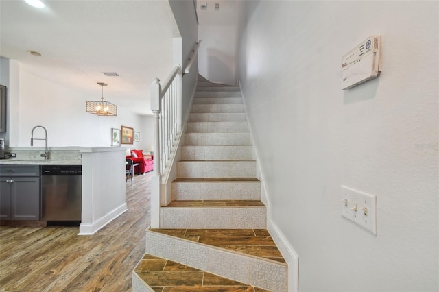 stairs featuring hardwood / wood-style flooring and sink