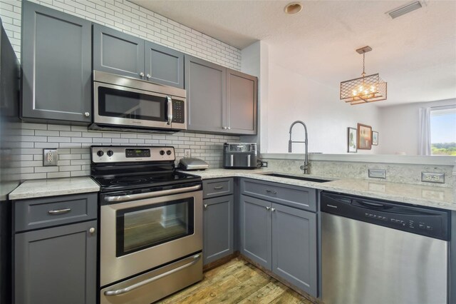 kitchen featuring sink, gray cabinetry, a chandelier, stainless steel appliances, and light hardwood / wood-style floors