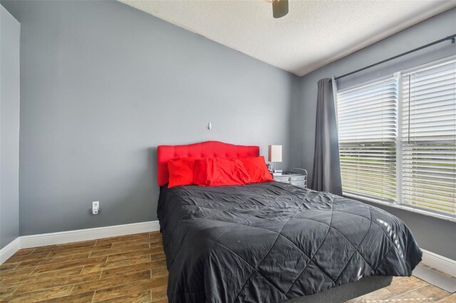 bedroom featuring ceiling fan, a textured ceiling, dark hardwood / wood-style flooring, and multiple windows