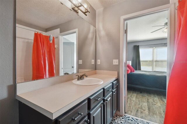 bathroom featuring ceiling fan, hardwood / wood-style flooring, vanity, and a textured ceiling