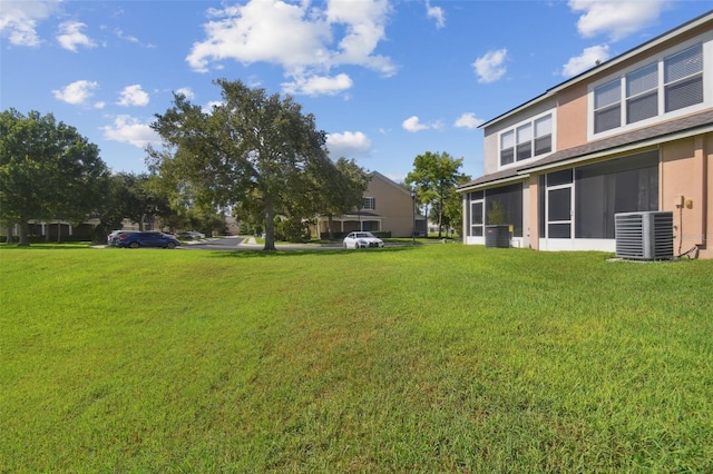 view of yard featuring a sunroom and central AC unit