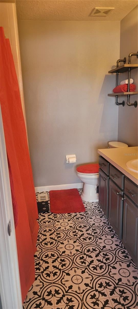 bathroom featuring vanity, toilet, and a textured ceiling