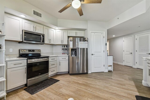 kitchen with appliances with stainless steel finishes, light hardwood / wood-style flooring, white cabinetry, and ceiling fan