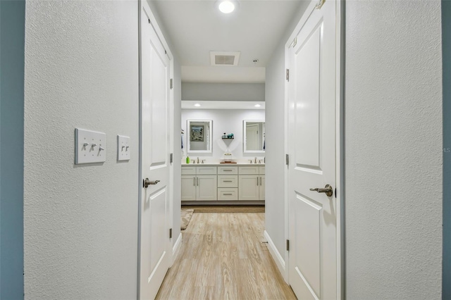 corridor featuring sink and light hardwood / wood-style floors