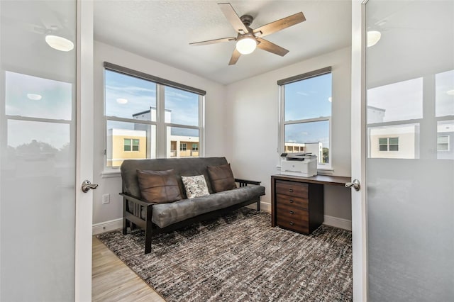 living area with light wood-type flooring, plenty of natural light, and ceiling fan