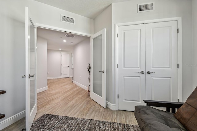 hallway with french doors and light hardwood / wood-style floors