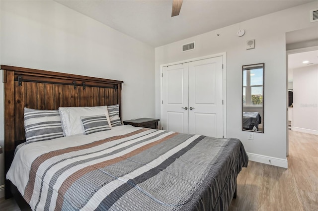 bedroom with light wood-type flooring, a closet, and ceiling fan