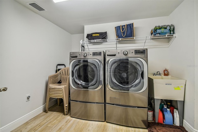 laundry room with separate washer and dryer and wood-type flooring