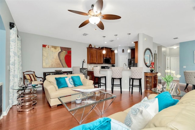 living room featuring dark wood-type flooring, ceiling fan, and sink