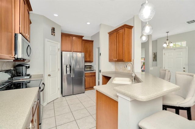 kitchen with a notable chandelier, a kitchen breakfast bar, kitchen peninsula, sink, and appliances with stainless steel finishes