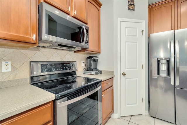 kitchen featuring light tile patterned floors, stainless steel appliances, and decorative backsplash