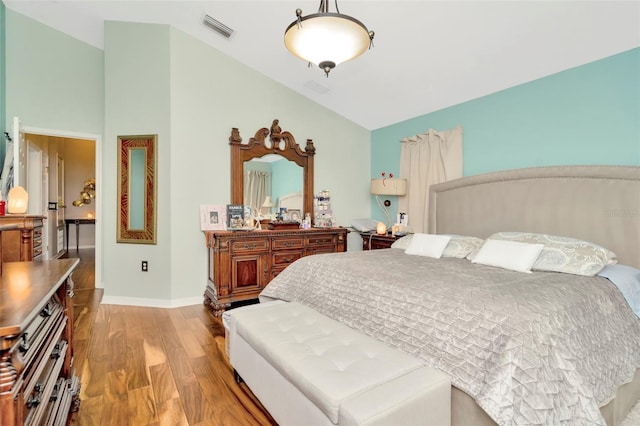 bedroom featuring high vaulted ceiling and light hardwood / wood-style flooring